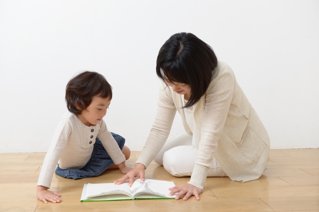 子供に絵本の読み聞かせをしているママ