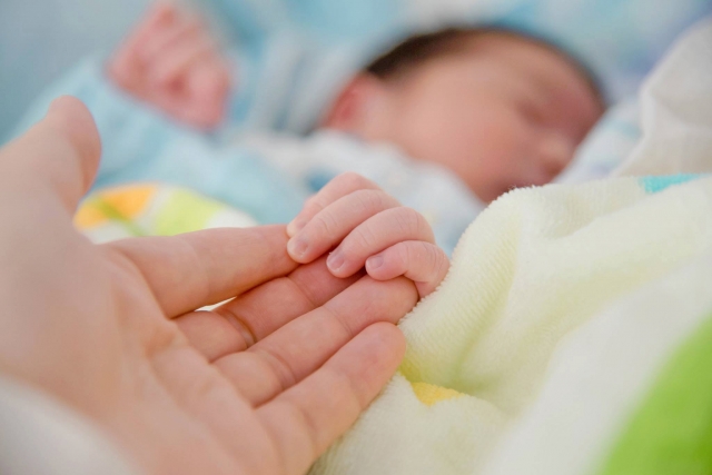 夜泣きをしないように赤ちゃんの手を握るママの手